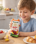 Child holding a box of Almaverde mela juice in a kitchen setting